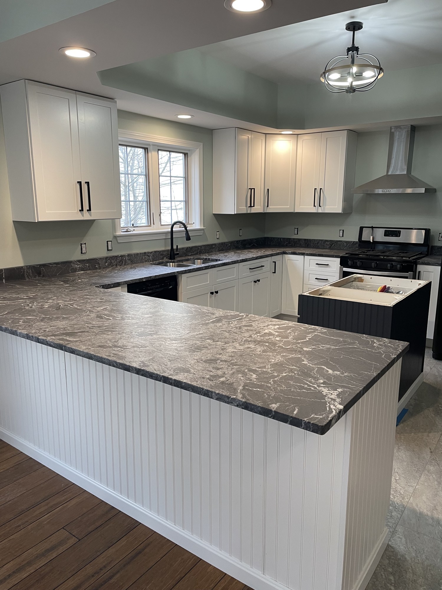 Remodeled kitchen with a bead-board island under dark granite and a tray ceiling