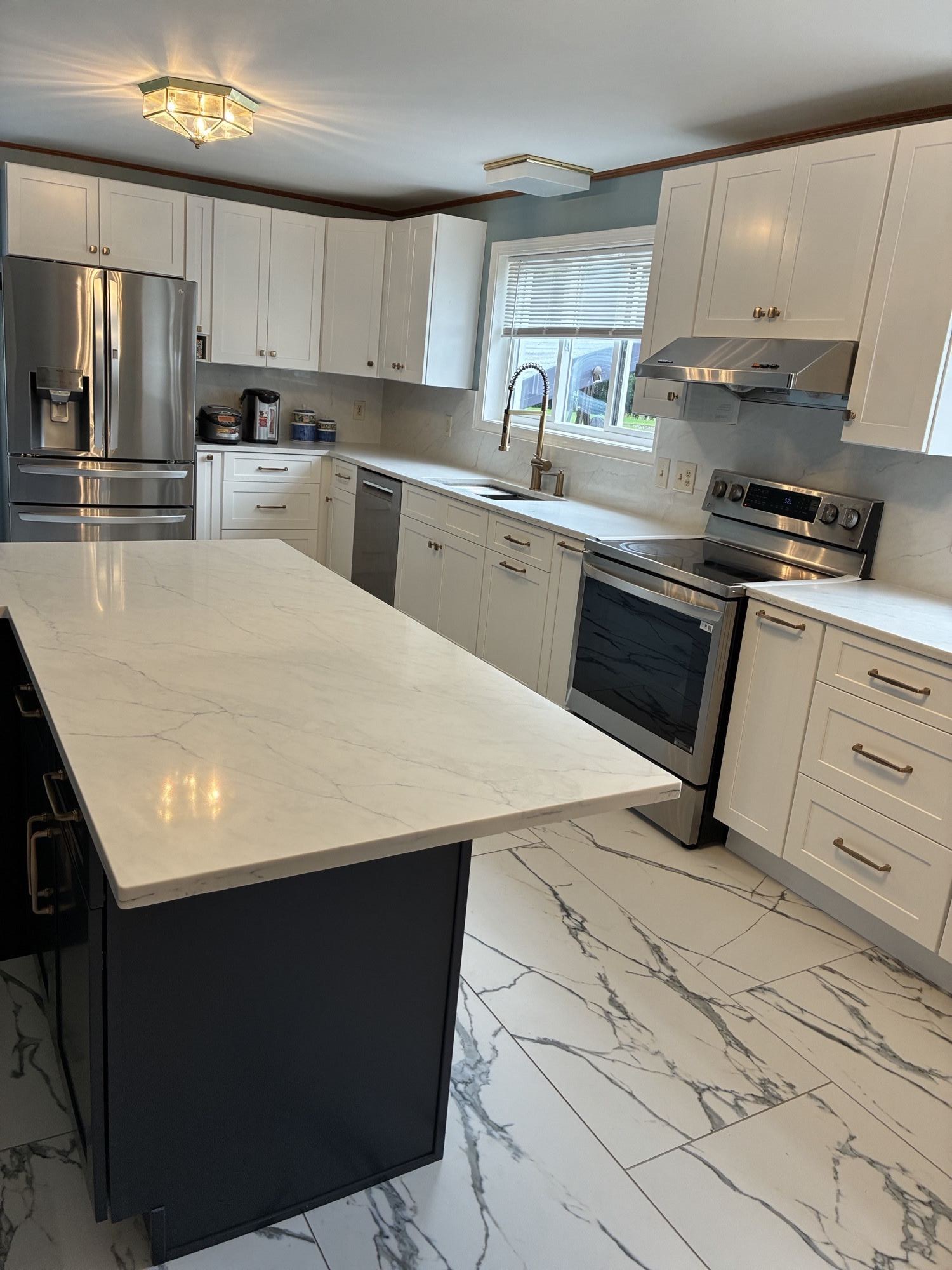 Remodeled kitchen with a navy island, quartz countertops and new tile floor